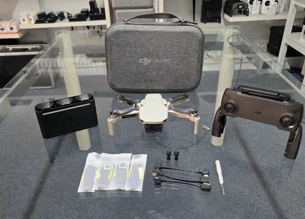 Pre-owned DJI Mavic Mini 1 Flymore Combo with drone, controller, spare props, and carrying case.