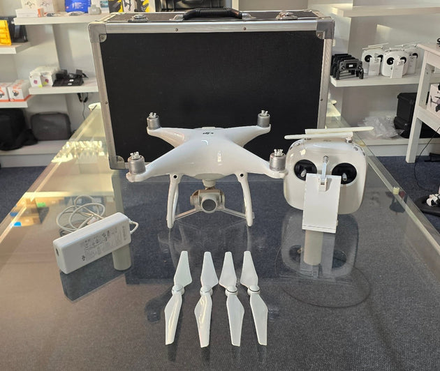 Pre-Owned DJI Phantom 4 Standard drone, controller, battery, charger, props, and carry case on display.